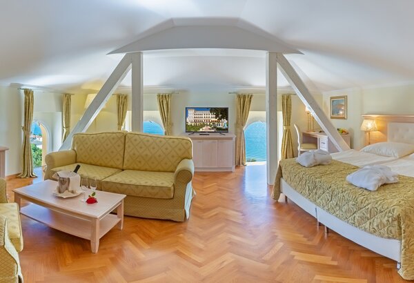 Geräumiges Hotelzimmer mit einem Doppelbett und einer gemütlichen Sitzecke. Große Fenster bieten einen Blick auf das Wasser. Helle Farben und Holzfußboden schaffen eine einladende Atmosphäre. Ein F... Appartements für Familienurlaub Crikvenica, Kroatien