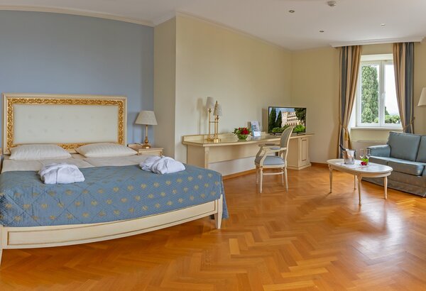 Geräumiges Hotelzimmer mit einem großen Doppelbett, einem gemütlichen Sofa und einem Tisch. Helle Wände und Holzfußboden schaffen eine einladende Atmosphäre. Ein Fernseher und ein Schreibtisch sind... 4-Sterne-Hotel am Meer Kroatien ☛ Superior Doppelzimmer